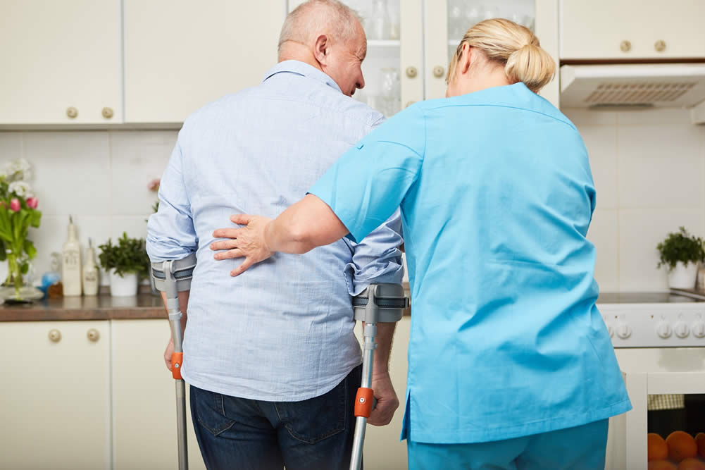 Caregiver helping a senior on crutches